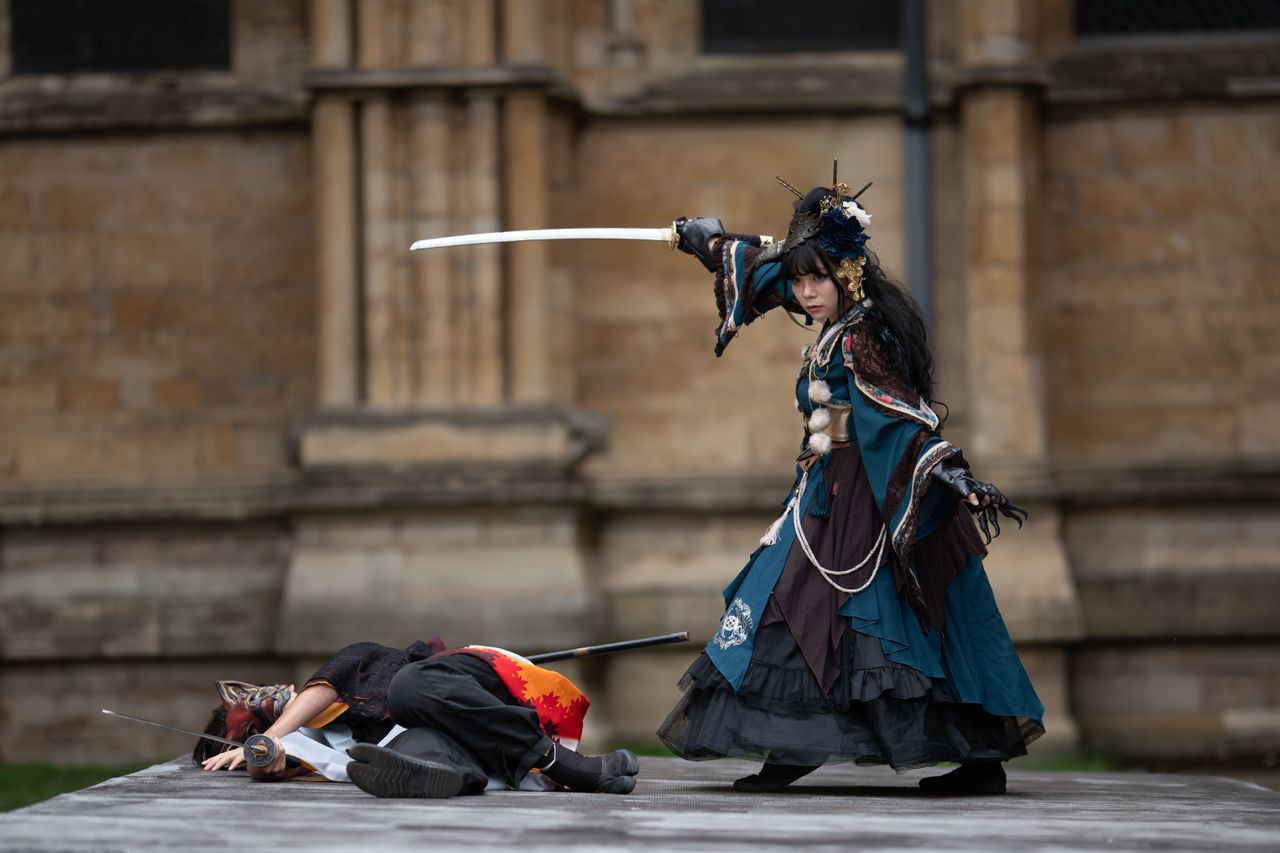 Dramatic outdoor cosplay scene with sword fight and elaborate costumes.