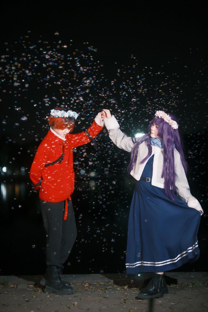 A couple in costume dances at night surrounded by bubbles.