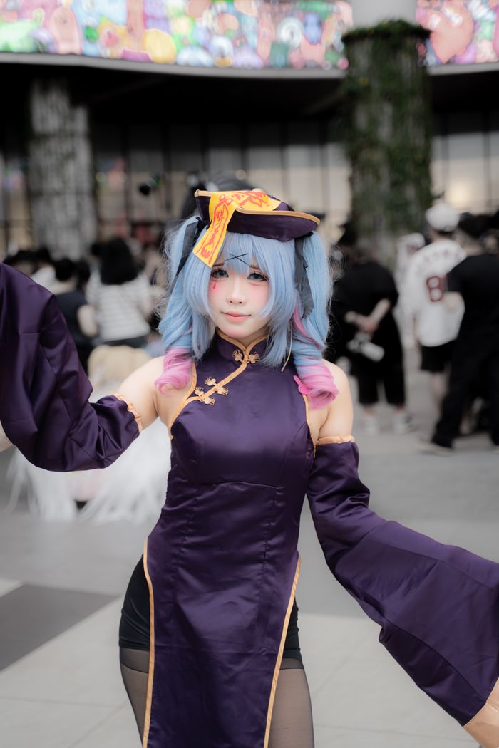Cosplayer in colorful attire poses at lively outdoor event with crowd.