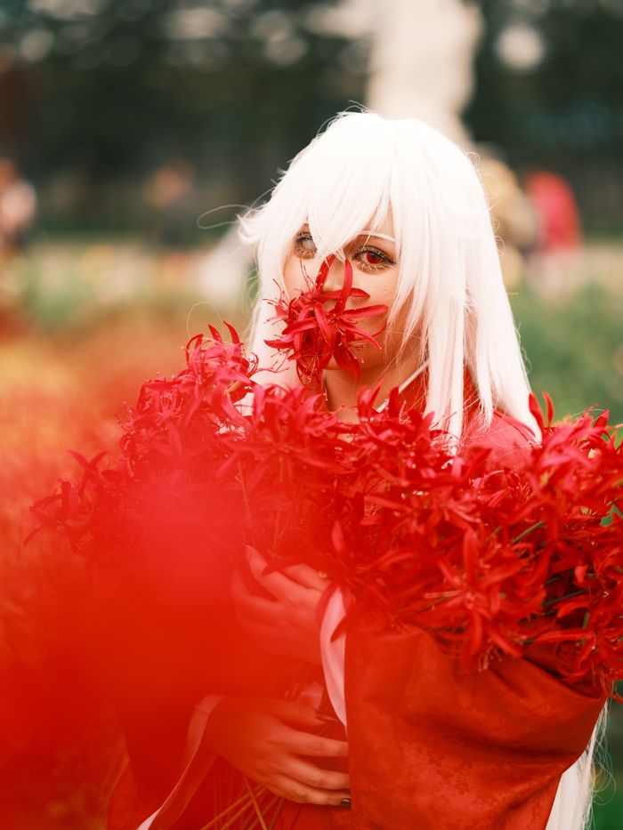 Immersive cosplay scene in vibrant red florals, captured outdoors in Vietnam.