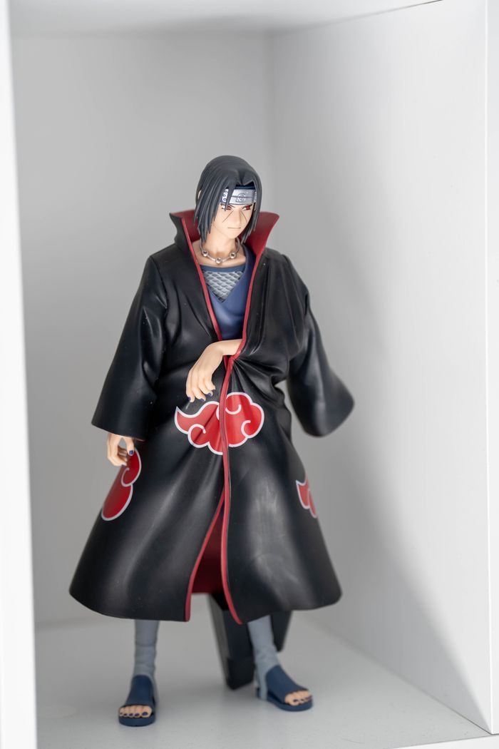 Detailed anime figure in black cloak with red cloud pattern on display shelf.
